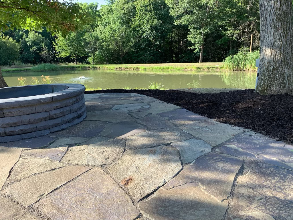 Tight-gapped Pennsylvania flagstone patio with a curved block seating wall at the pond edge