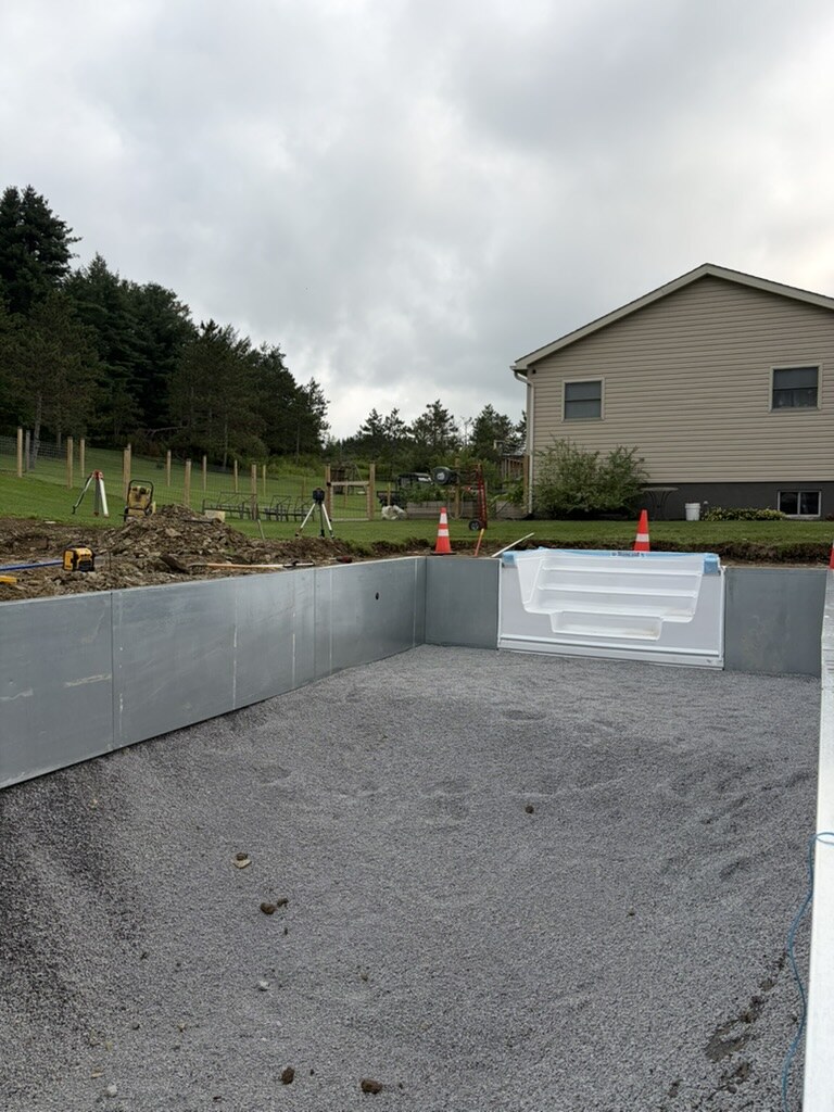 Inside a new in-ground pool: compacted gravel floor, steel walls and the white entry steps