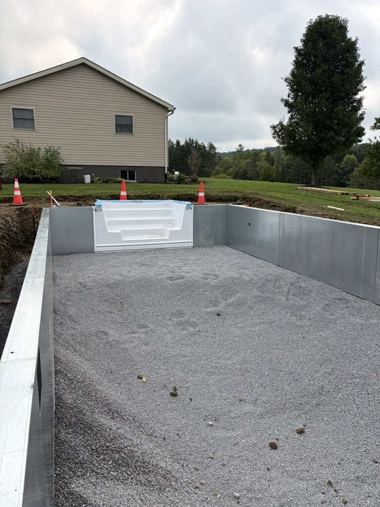 Steel-wall in-ground pool with the white step unit set, viewed from the deep end toward the house