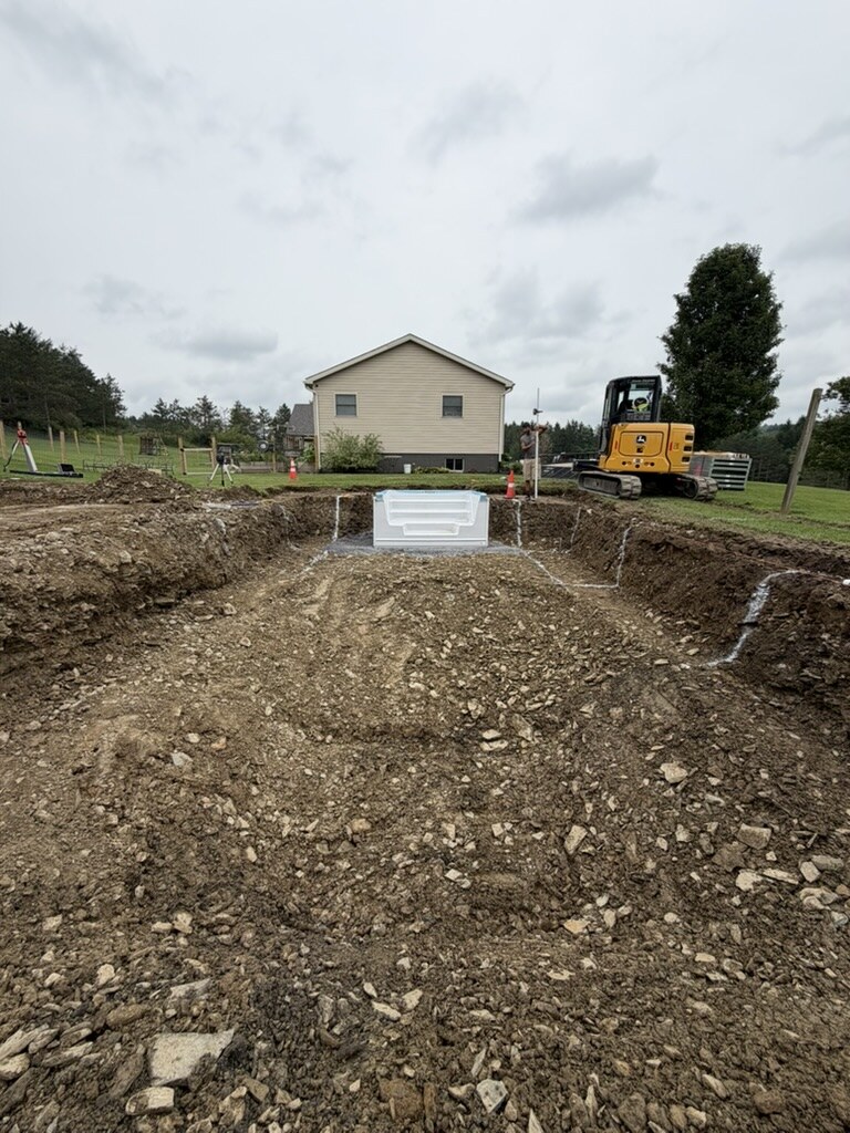 Excavated in-ground pool hole with the fiberglass step unit positioned at the shallow end