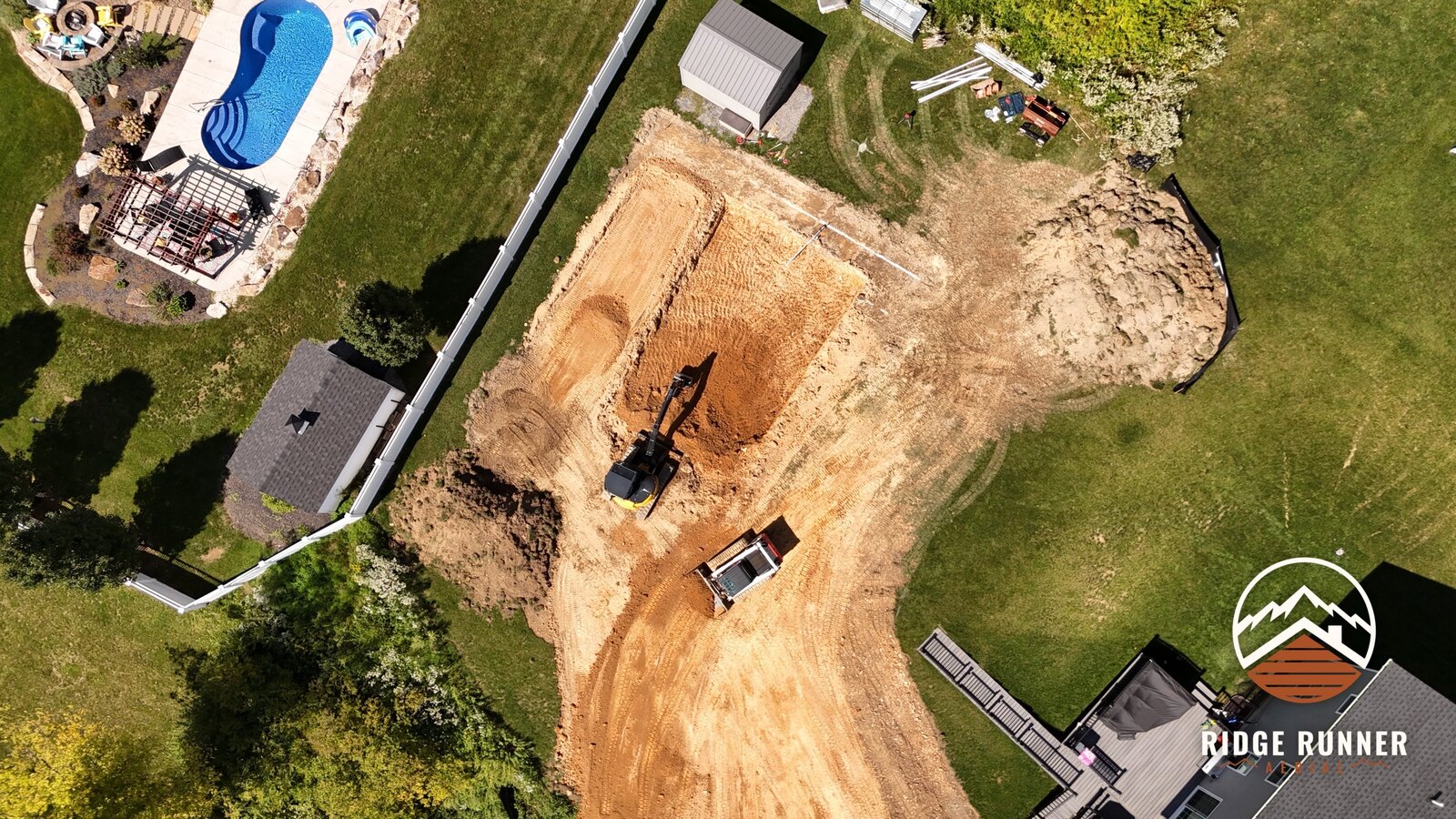 Top-down aerial of the squared pool hole with the excavator working the shallow end in Hollidaysburg, PA