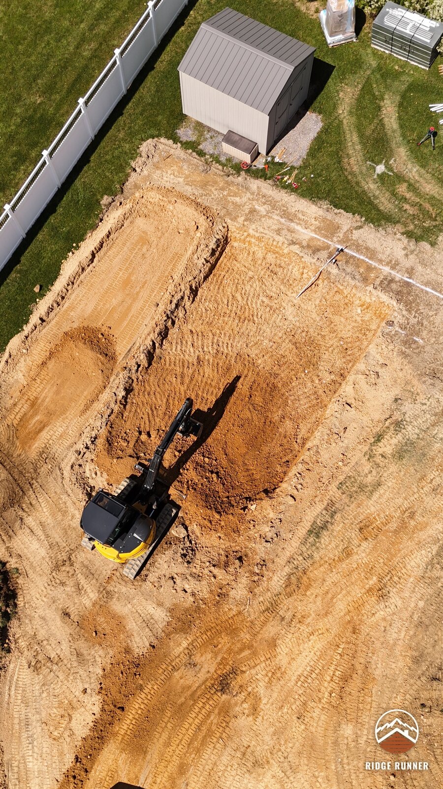 Close top-down aerial of the excavator finishing the pool floor beside the shed in Hollidaysburg, PA